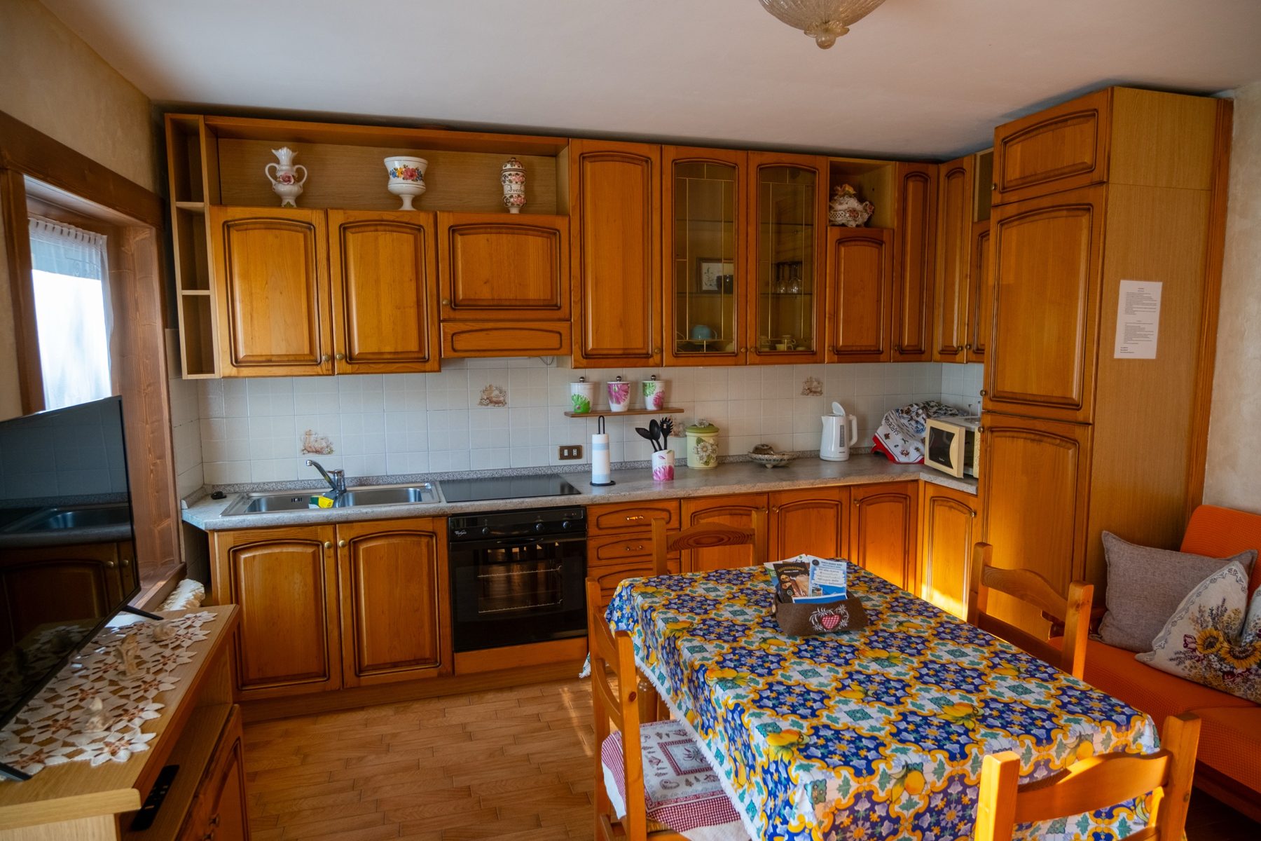 Cucina in legno con piano a induzione, forno, microonde e tavolo