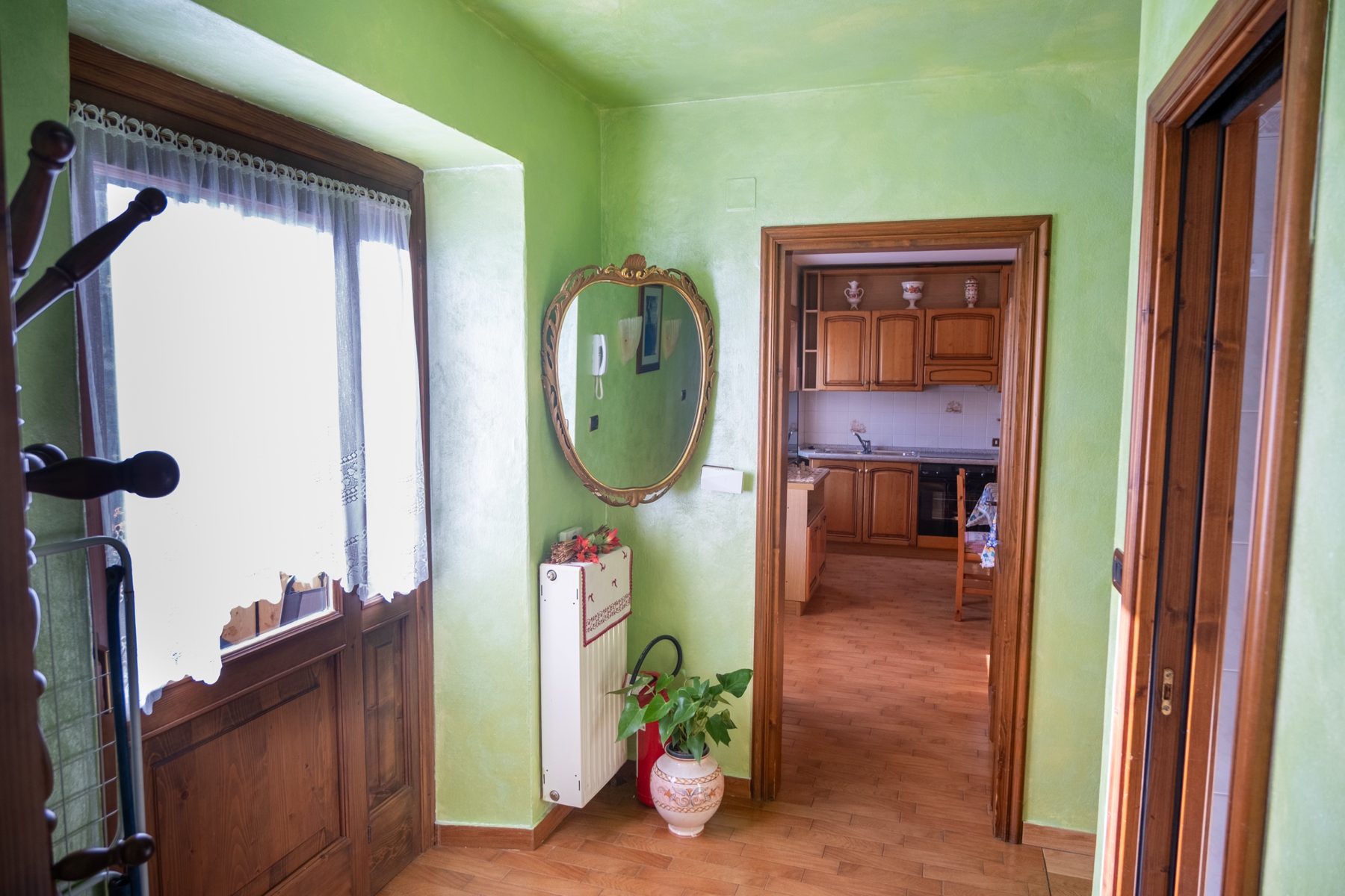 Ingresso con specchio e porta aperta sulla cucina